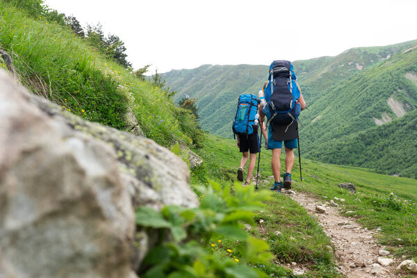 Trekking in mountains. Climbers with backpacks hiking in mountain trail