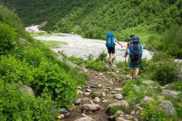 Dağlarda trekking. Sırt çantaları turistlerle dağ nehri geçmek. Vahşi dağlar'da yürüyüş. — Stok fotoğraf