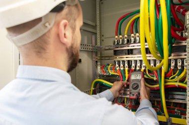 Elektrik kabininde multimetre ile çalışan elektrikçi