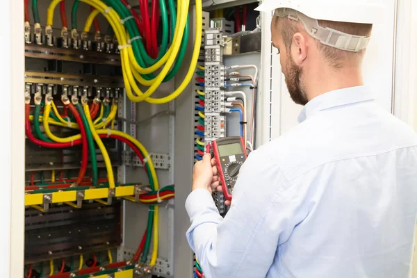 Elektricien Engineer met meetinstrument werkt in elektrische cabine — Stockfoto