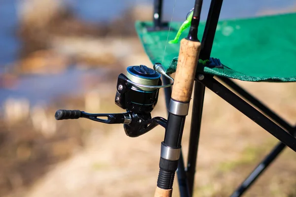 Bobina di pesca su filatura sul fondo del lago primo piano. attrezzi da pesca sulla sedia — Foto Stock