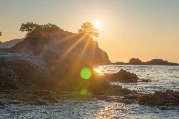 Ljus soluppgång på havet stranden i Lloret de Mar. solen skiner över Roc — Stockfoto