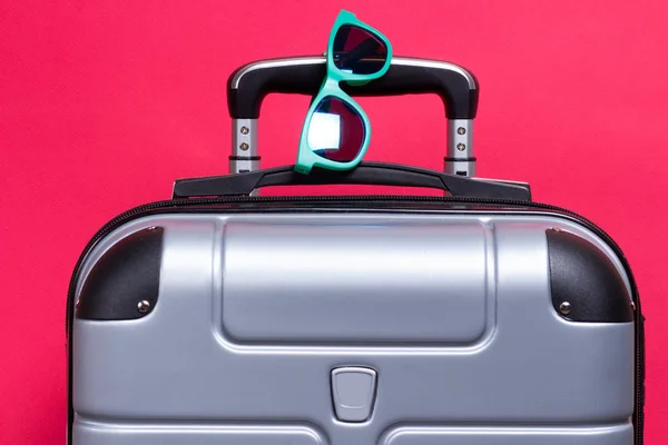 Βαλίτσα με γυαλιά ηλίου σε ροζ φόντο. Καλοκαιρινό ταξίδι — Φωτογραφία Αρχείου