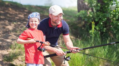 Baba ve oğul göl kenarında balık tutuyor. Balık tutan bir adam ve çocuk.