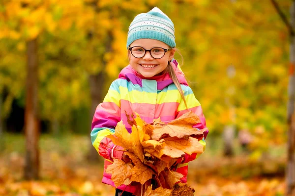 Ritratto autunnale di una bambina con foglie gialle nelle mani — Foto Stock