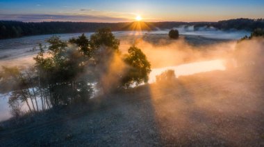 Yaz manzarası. Sisli gün doğumu. Güneşin altında sisli bir nehir. 