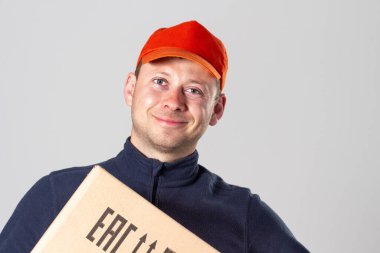 Karton kutulu teslimat servisi üniformalı adam. Dost canlısı teslimatçı gülümser ve kağıt kutu tutar..