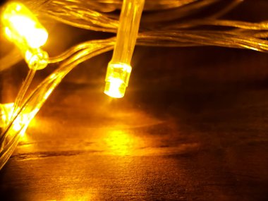 Tahta bir yüzey üzerinde duran sarı LED dizgi ışıklarının yakın çekim görüntüsü.