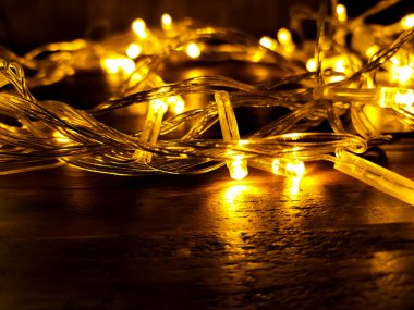 Tahta bir yüzey üzerinde duran sarı LED dizgi ışıklarının yakın çekim görüntüsü.