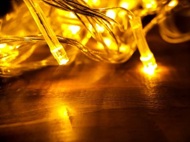 Tahta bir yüzey üzerinde duran sarı LED dizgi ışıklarının yakın çekim görüntüsü.