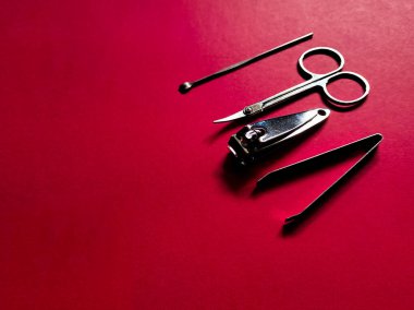 Kırmızı bir yüzeye yerleştirilmiş bir takım manikür araçları