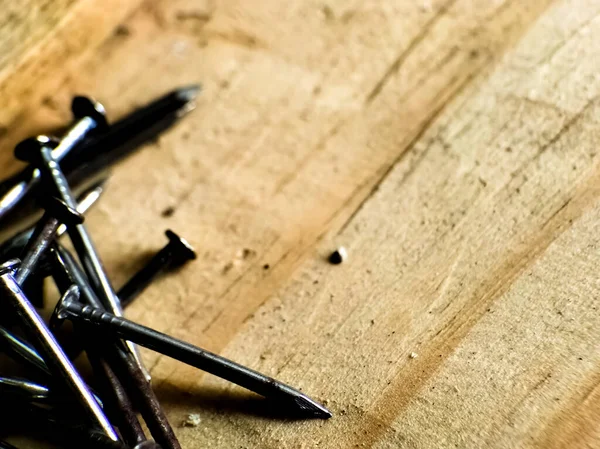 Tahta bir yüzeye saçılmış gümüş metal çiviler.. 