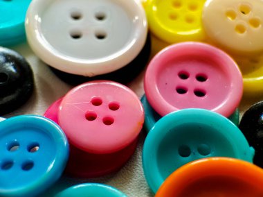 A collection of brightly colored sewing buttons is arranged on a white textured surface