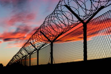 Gün batımında karanlık barbwire çit