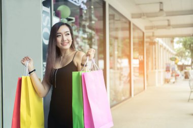 Asyalı kadın yol City shopping yakınındaki alışveriş çantası elinde.