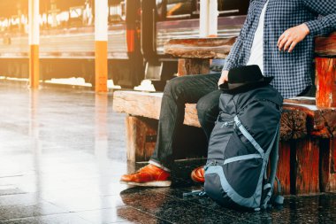 gelmesini tren ile tren istasyonunda oturan Asya hipster genç adam.