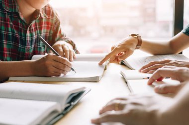 Öğrencilerin kütüphanede ödev hakkında beyin fırtınası için yardımcı oluyor.