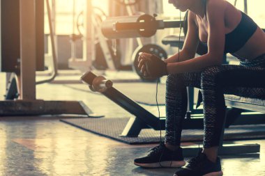 Asyalı kadın spor salonunda cep telefonu ve dinlemek müzik kullanma.