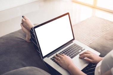 Safa üzerinde oturan ve evde dizüstü bilgisayar boş ekran kullanarak kadın.