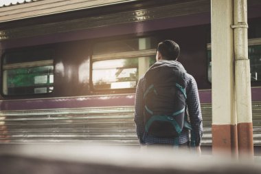 Asya genç hipster adam ayakta ve platform üzerinde tren bekleyen arkadan görünüş.