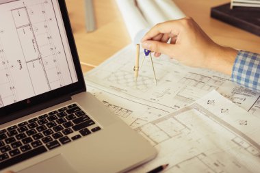 Mimar blueprint dizüstü bilgisayar ile işyerinde çalışan ve pusula çizim.