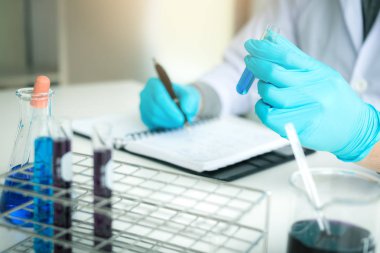 Test tüpü incelenmesi ve yazma reaktif laboratuvar araştırmacı konsepti ile not edin tutarak Asya bilim adamı.