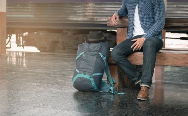 gelmesini tren ile tren istasyonunda oturan Asya hipster genç adam.
