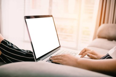 Trackpad yazarak ve şezlong üzerinde oturan ve evde dizüstü bilgisayar boş ekran kullanarak kadın eli kapatın.