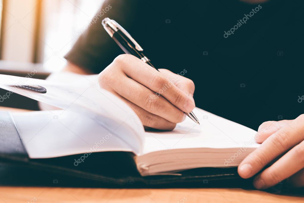 People writing making note on notebook.