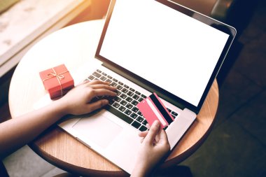 Kredi kartı online alışveriş yaparken ve dizüstü bilgisayar boş ekran görünümü kadın el ile yukarıda tutarak.