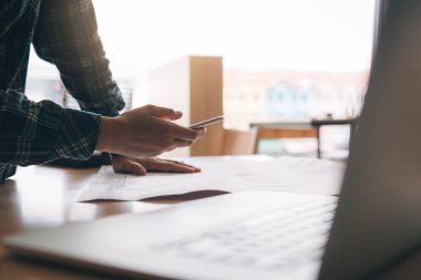 Ayakta Smartphone'da yazarak ve modern ofisinde çalışan mimar.