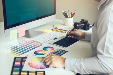 Şirket ofisinde oturan ve dijital grafik tablet üzerinde çalışan genç tasarımcı.
