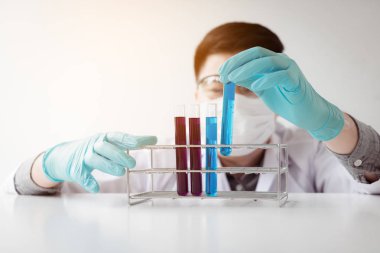 Genç Asyalı adam tıbbi araştırmacı laboratuarda test tüpleri cam arıyorsunuz.