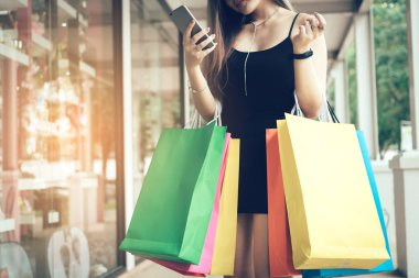 Smartphone kullanarak ve satış promosyon alışveriş torbaları holding ile kontrol kadın.
