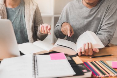 Öğrencilerin kütüphanede ödev hakkında beyin fırtınası için yardımcı oluyor.
