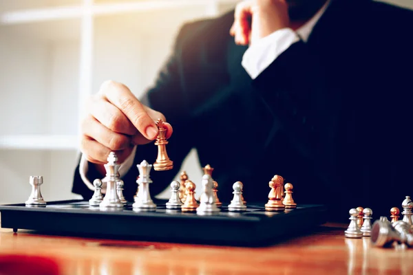 Businessman thinking about strategy concept and hand moving the king in a chess game for win.