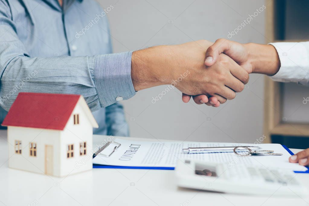 Close up of shaking hands with customer and real estate broker after signing a contract in home office.