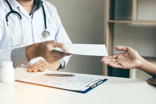 Asyalı erkek doktor klinikte konuşuyor ve hastaya reçete veriyor..