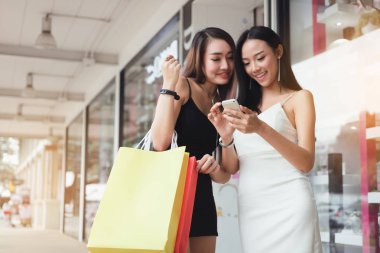 İki güzel kadın alışveriş merkezinde smartphone kullanarak.