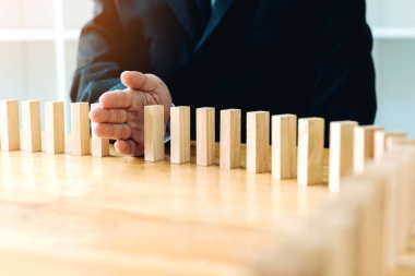 Domino ile risk kavramı doğrultusunda düşmesini ahşap blok durdurma el işadamı kapatmak.