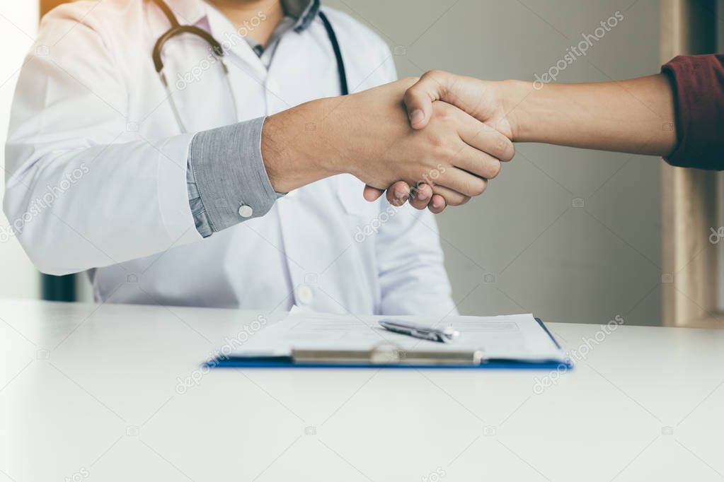 Doctor shaking hands with older patient in the office.