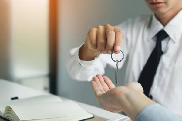 Close up hand of home agents are handing out keys to new home buyers.