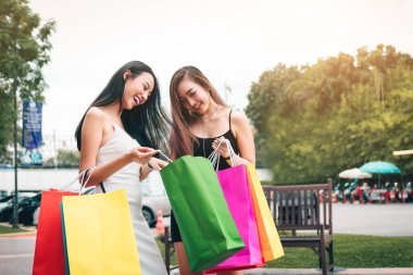 Outlet Alışveriş Merkezi ayakta ve alışveriş torbaları kağıt içinde seyir iki Asyalı kadınlar.