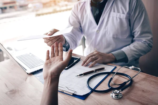 Asyalı erkek doktor klinikte konuşuyor ve hastaya reçete veriyor..