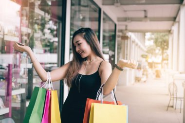 Asya genç kadının kağıt torba taşıyan ile outlet alışveriş merkezi alışveriş keyfi.