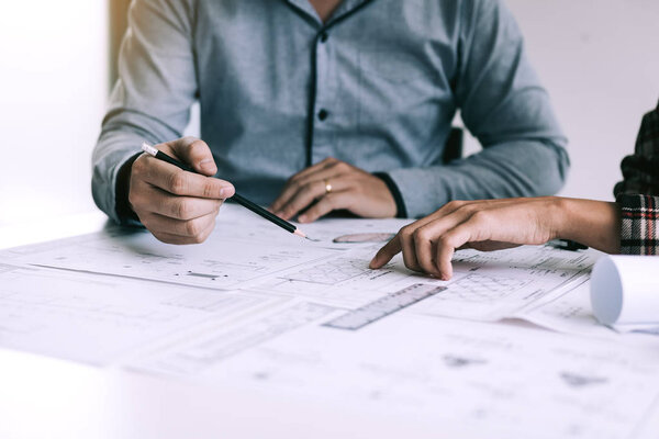 Архитекторы или инженеры, работающие с чертежами и обсуждающие проект вместе на встрече в офисе
.