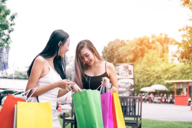 Outlet Alışveriş Merkezi ayakta ve alışveriş torbaları kağıt içinde seyir Asyalı kadınlar.