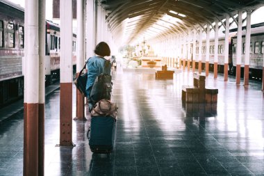 Arkadan görünüş Asyalı erkeklerin sürükleyin çanta tren istasyonunda.