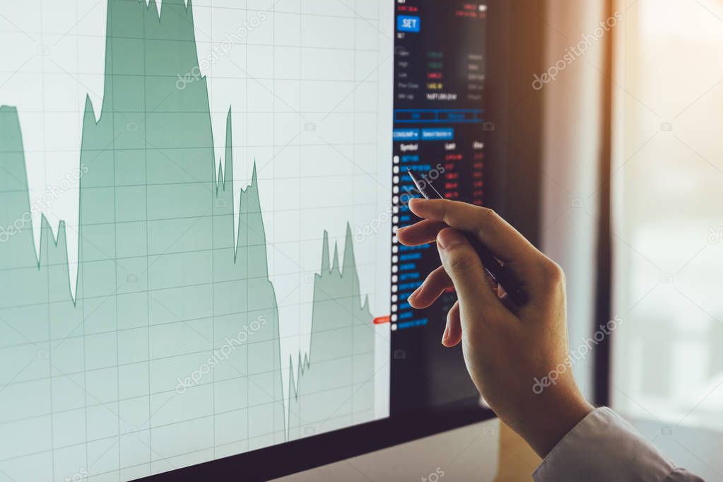 Close up of businessman hand pointing to stock market chart and analysis on computer screen.