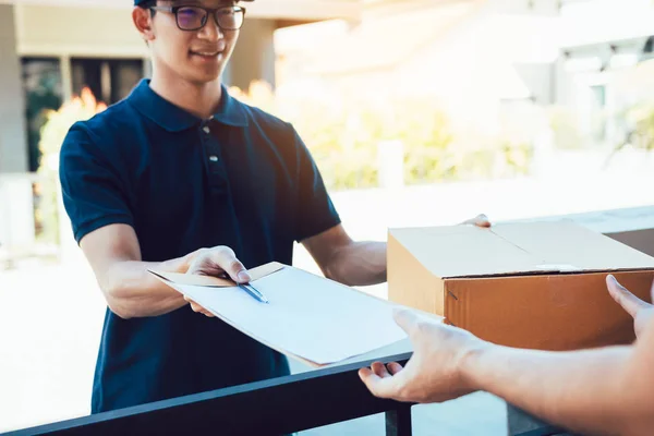 Joven asiático hombre sonriendo mientras la entrega de una caja de cartón a la — Foto de Stock